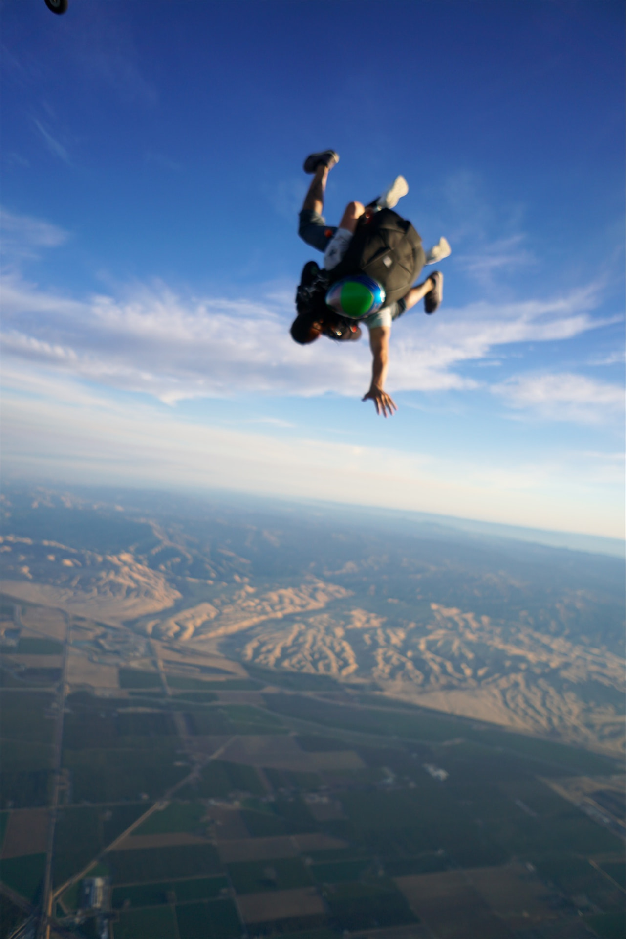 Skydiver in freefall above farmland