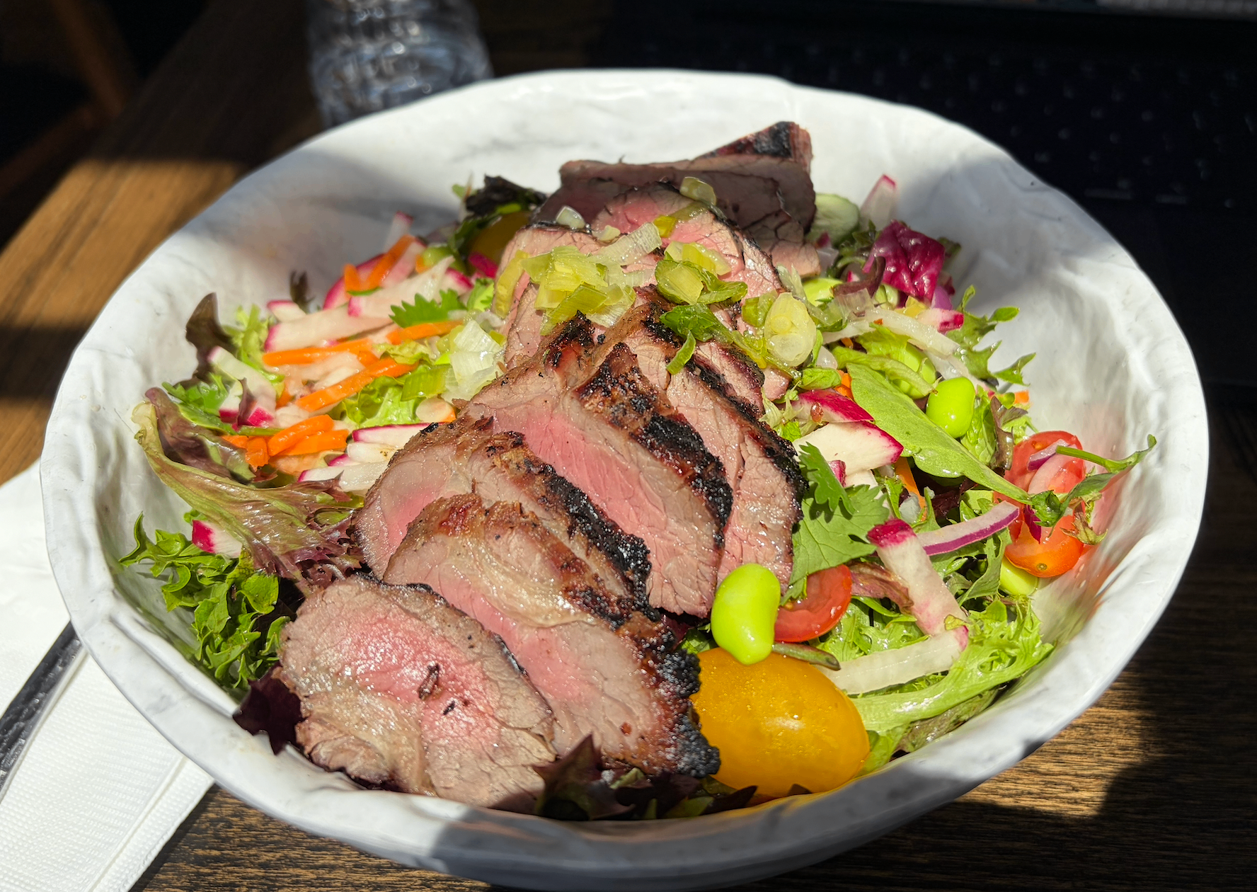 Steak salad in a white bowl