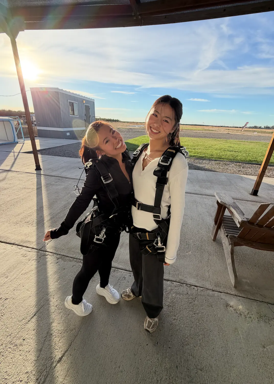 Two friends in skydiving harnesses at golden hour